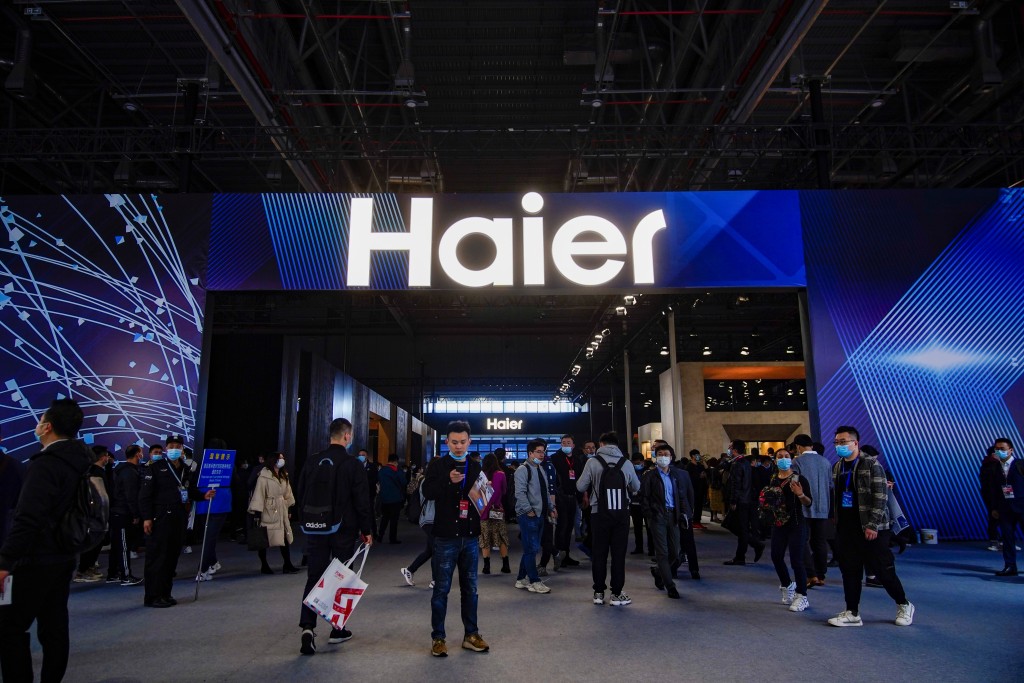 People stand under a Haier company sign at the Appliance and Electronics World Expo (AWE) in Shanghai, China March 23, 2021.  REUTERS/Aly Song