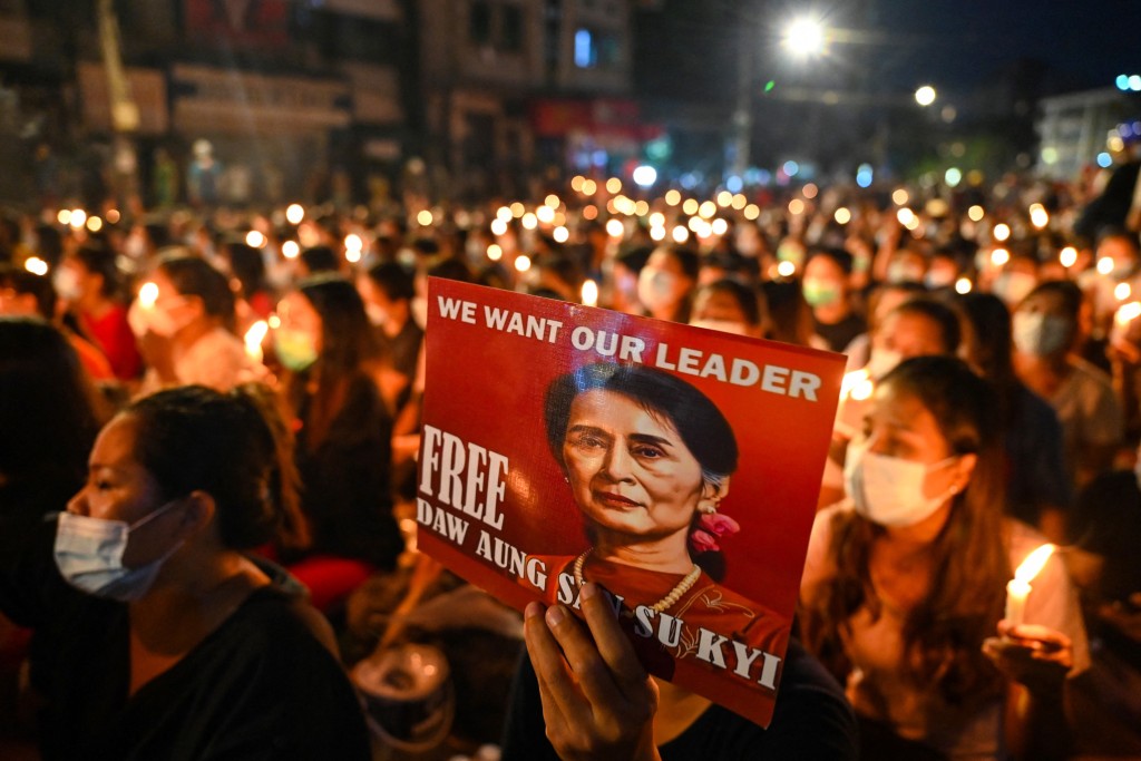 Photo by STR / AFP  A protester holds a poster with an image of detained civilian leader Aung San Suu Kyi during a candlelight vigil to honour those who have died during demonstrations against the military coup in Yangon on March 13, 2021.