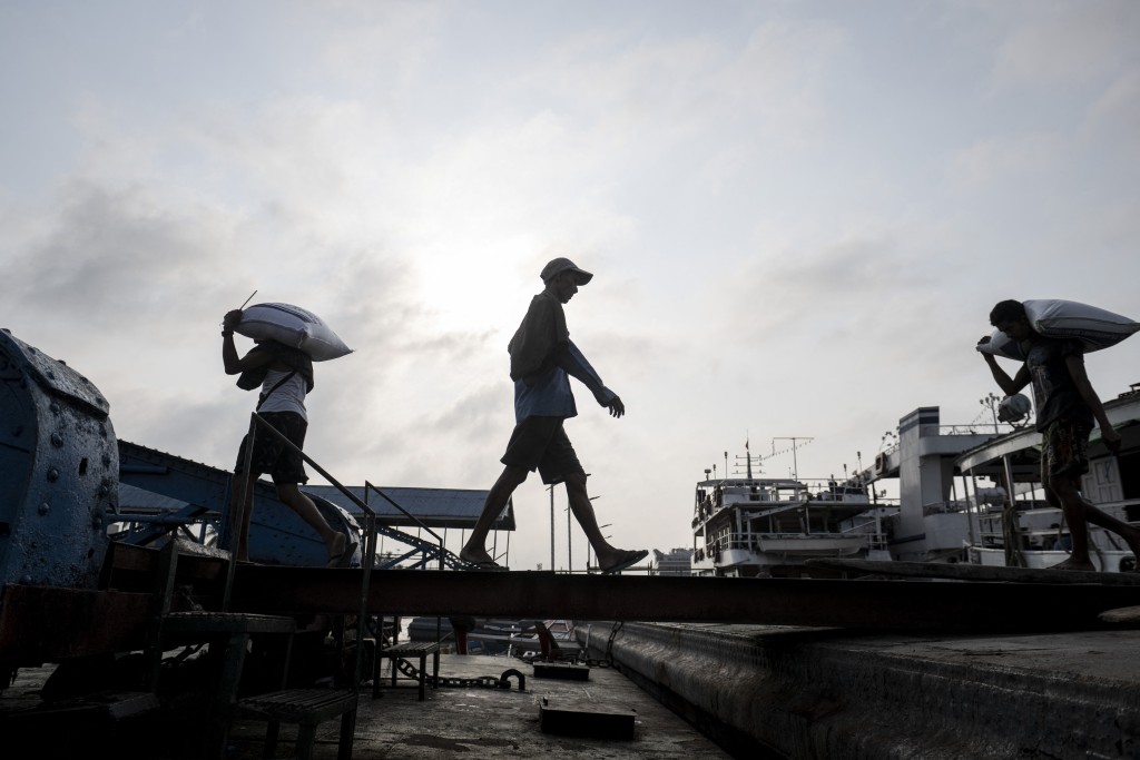Labourers unload sacks of rice from a ship along a jetty in Yangon. (AFP)