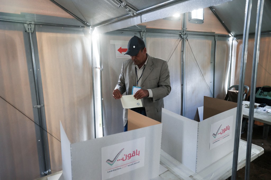 Photo by EYAD BABA / AFP. A Palestinian man prepares to cast his ballot at a polling station during municipal elections in Deir el-Balah, Gaza Strip, on April 25, 2026.