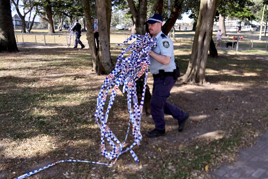 Photo by DAVID GRAY / AFP  Police officers remove police tape from the scene of Sunday’s shooting at Bondi Beach, in Sydney on December 17, 2025.