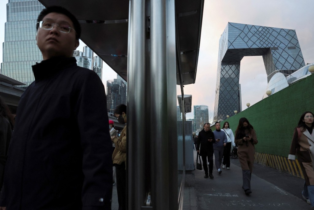 Commuters wait at a bus stop during rush hour in Beijing's central business district in March. Photo by REUTERS