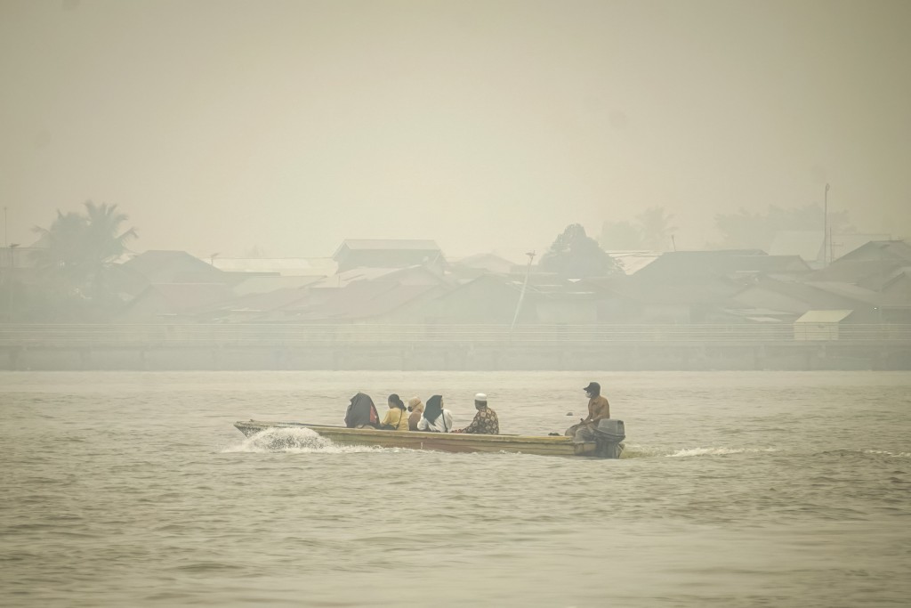 Photo by DITO / AFP  People travel on a river boat as thick haze from forest and land fires blankets Benua Melayu Darat village in Pontianak, West Kalimantan, on September 16, 2026.