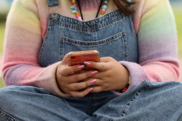 A girl uses her mobile phone in Sydney, Australia, November 22, 2025. REUTERS/Hollie Adams