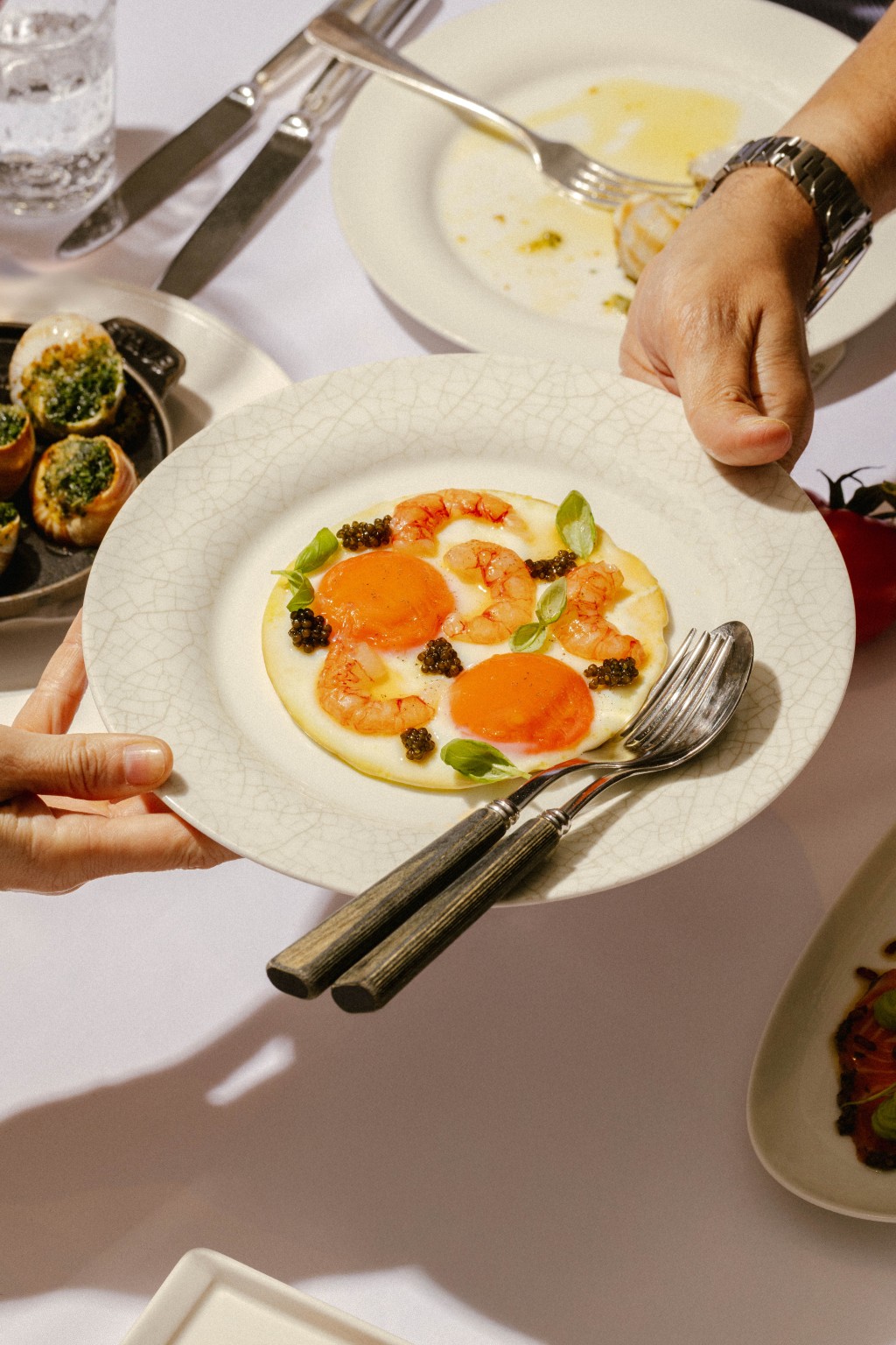 Sunny Side Up Eggs served with blue crystal prawns, fresh basil, and briny pops of caviar.