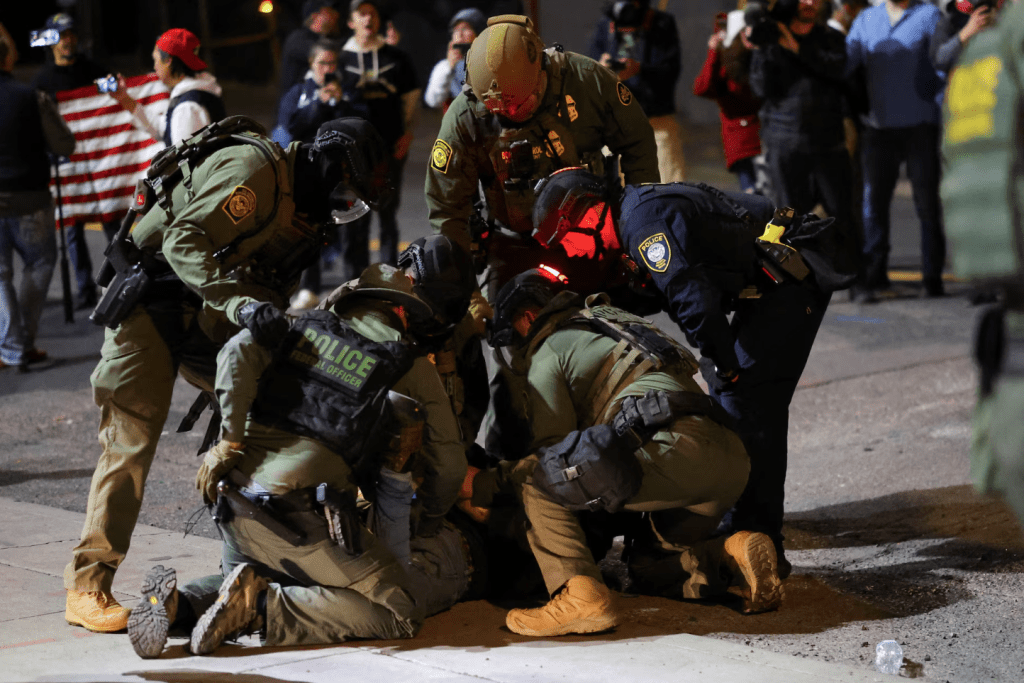 Law enforcement officers detain a protester outside the U.S. Immigration and Customs Enforcement (ICE) headquarters in south Portland, Oregon, U.S., October 5, 2025. (REUTERS/Carlos Barria)
