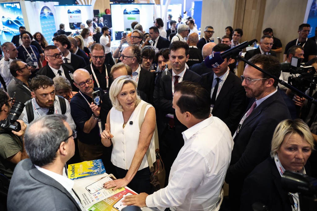 President of Rassemblement National parliamentary group Marine Le Pen (C) speaks with members of staff at the stand of French open source software editor Linagora during a visit of the VivaTech technology startups and innovation fair at the Paris Expo Porte de Versailles, in Paris on June 19, 2026. (Photo by SIMON WOHLFAHRT / AFP)