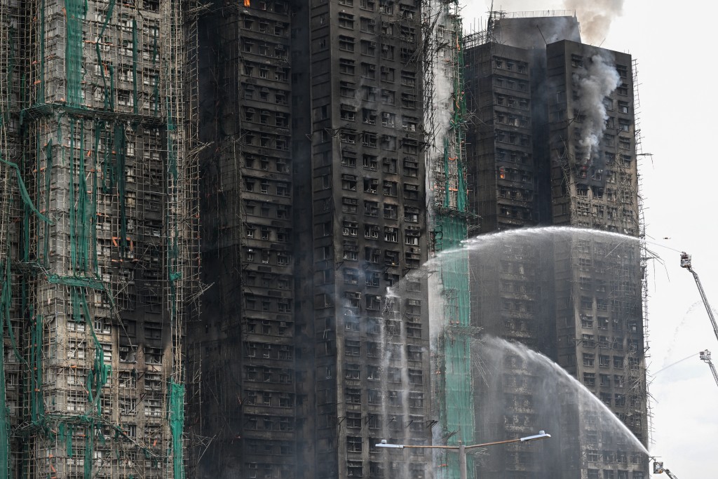 Photo by PETER PARKS / AFP  Firefighters spray water on flames as a major fire burns through several apartment blocks at the Wang Fuk Court residential estate in Hong Kong's Tai Po district on November 27, 2025.