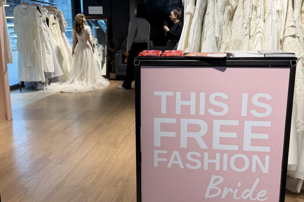 Photo by STEPHANIE HAMEL / AFP  Sustainable development communications specialist and bride-to-be Lara Beters examines her second-hand wedding dress in a "Free Fashion" pop-up shop shortly before her wedding inside Utrecht train station as part of an initiative to highlight sustainability issues, in Utrecht on April 2, 2026.