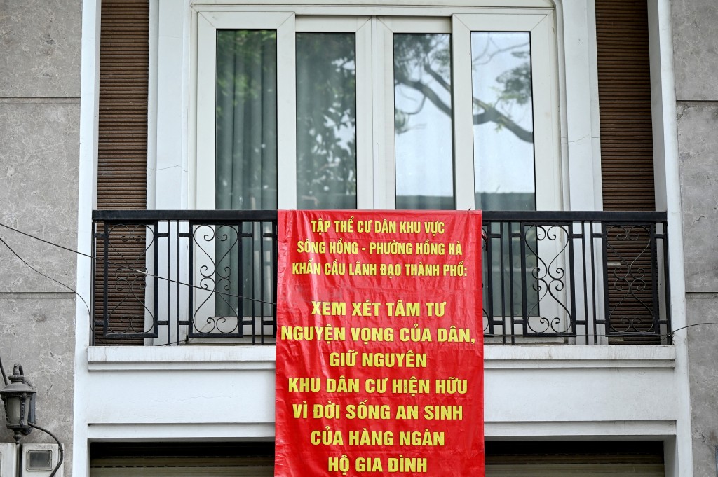 Photo by STR / AFP This photo taken on June 19, 2026 shows a protest banner, which reads “The residents of the Red River area in Hong Ha Ward earnestly appeal to city leaders to consider the people's inner thoughts and aspirations, maintaining the existing residential area for the sake of the well-being of thousands of households”, hanging from the front balcony of a residence in Hanoi.