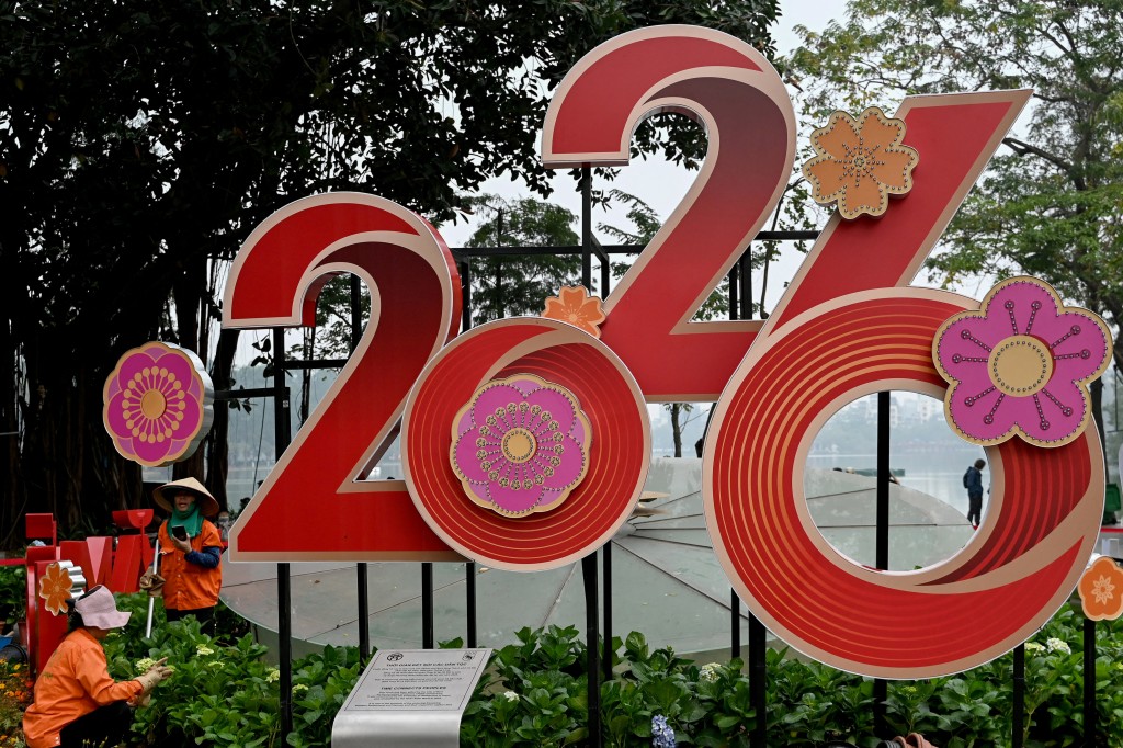 Workers tend to flowers next to a 2026 New Year banner in Hanoi on December 31, 2025. (AFP)