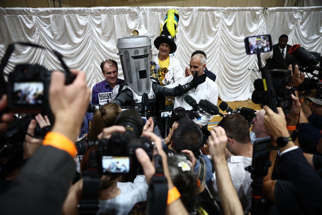 Photo by HENRY NICHOLLS / AFP Candidates, including Count Binface (C), poses with other candidates following the declaration of the Clacton by-election at Clacton Leisure Centre, eastern England on August 14, 2026.