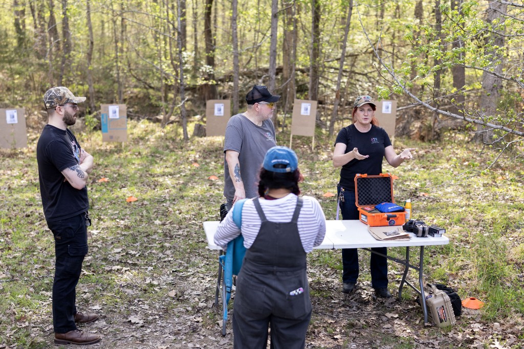 Photo by RYAN M. KELLY / AFP  Tony Talbert (C) and Clara Elliott (R) teach an introductory firearms class at a backyard shooting range in Midlothian, Virginia, on April 11, 2026.