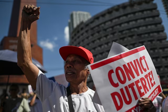 A protester raises a clenched fist as he holds a placard during a rally before former Philippine President Rodrigo Duterte's pre-trial hearings on his alleged crimes against humanity case at the International Criminal Court, in Quezon City, Metro Manila, Philippines, February 23, 2026. REUTERS/Noel Celis