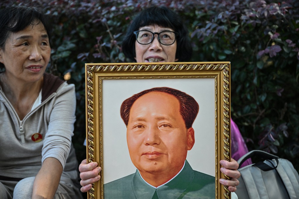 A woman holds a portrait of late Communist leader Mao Zedong while paying tribute at the Mao Zedong Bronze Statue Square in Shaoshan, China's central Hunan province on September 9, 2026, during the 50th anniversary of his death. (Photo by Hector RETAMAL / AFP)