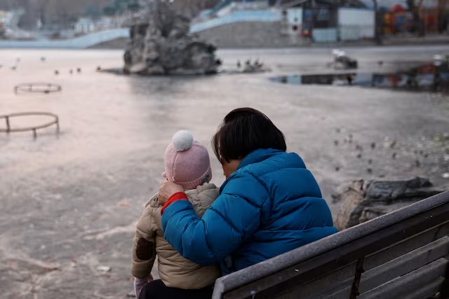 A woman and a child sit in a park in Beijing, China January 12, 2024. REUTERS/Tingshu Wang 