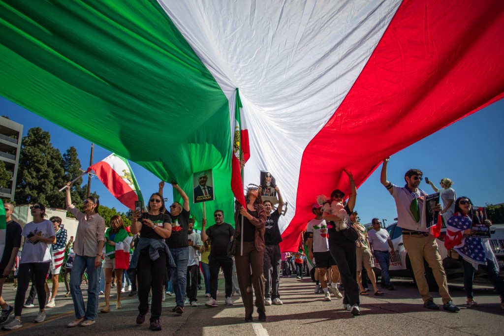 People walk under a Iranian pre-1979 Islamic Revolution flag in Los Angeles, on February 28, 2026. (AFP)