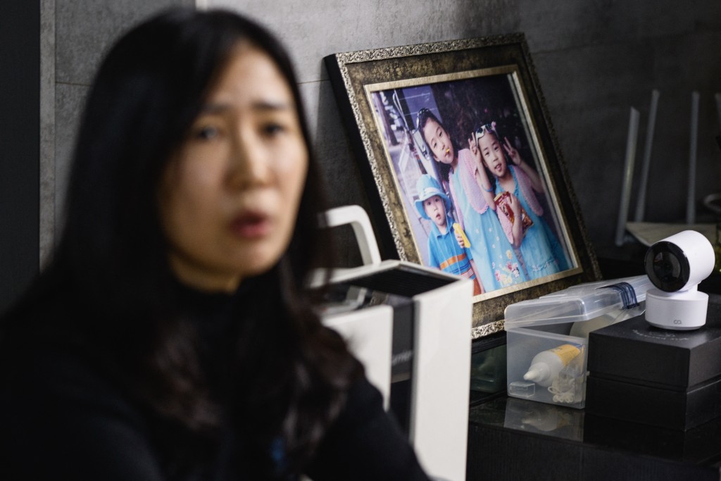 Photo by ANTHONY WALLACE / AFP  In this photo taken in Gwangju on December 14, 2025, Lee Hyo-eun sits next to a photo of her three children, including her daugher Ye-won, who died along with 178 others in the Jeju Air Flight 2216 plane crash on December 29, 2024.
