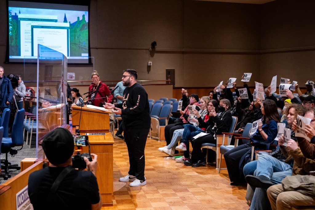 Photo by ADAM GRAY / AFP  An anti-ICE and Border Patrol protestor speaks before demonstrators were removed by New Orleans Police Department officers for disrupting a city council meeting at City Hall in New Orleans, Louisiana, on December 4, 2025.