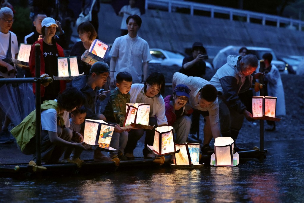 This photo taken on August 11, 2025 shows people releasing lanterns for the victims ahead of the 40th anniversary of the Japan Airlines Flight 123 crash, the world’s deadliest single-aircraft accident with 520 killed, on the river that flows at the foot of Mount Osutaka in Ueno Village, Gunma Prefecture. (Photo by JIJI PRESS / AFP) / JAPAN OUT