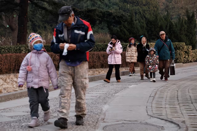 Elderly people walk with children at a park in Beijing, China January 12, 2024. REUTERS/Tingshu Wang/File Photo