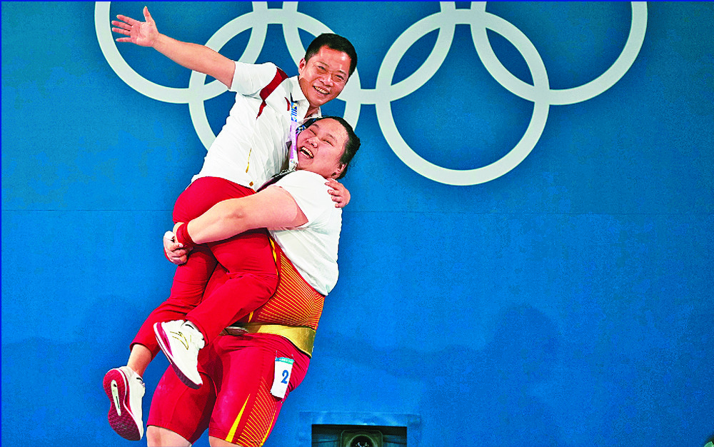 Li Wenwen hugs and lifts her coach after a smashing win in weightlifting as twins Wang Liuyi and Wang Qianyi snatch the gold in the duet free routine of artistic swimming.
AP, XINHUA Li Wenwen hugs and lifts her coach after a smashing win in weightlifting as twins Wang Liuyi and Wang Qianyi snatch the gold in the duet free routine of artistic swimming.
AP, XINHUA