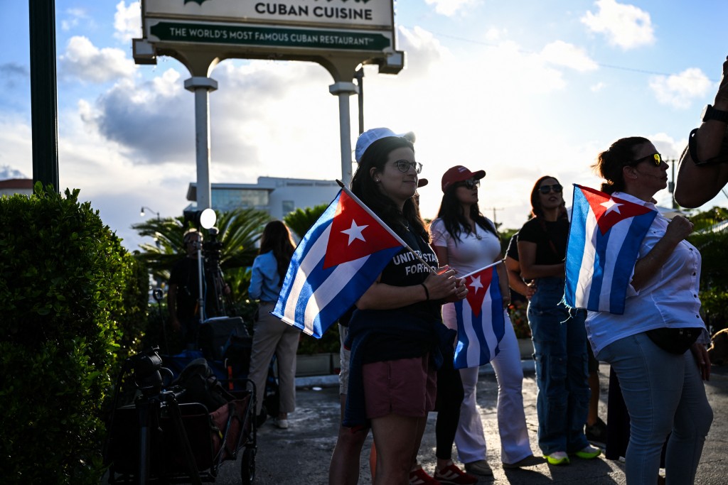 People hold Cuban flags as they gather outside Versailles Restaurant in support of charges announced by US federal prosecutors against the former Cuban president in Miami, Florida, on May 20, 2026. (AFP)