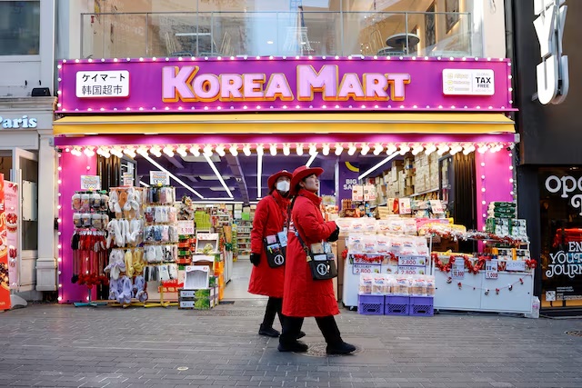 Tourist guides walk next to a Korean Mart at Myeongdong Street in Seoul, South Korea, December 5, 2024. REUTERS/Kim Soo-hyeon/File Photo