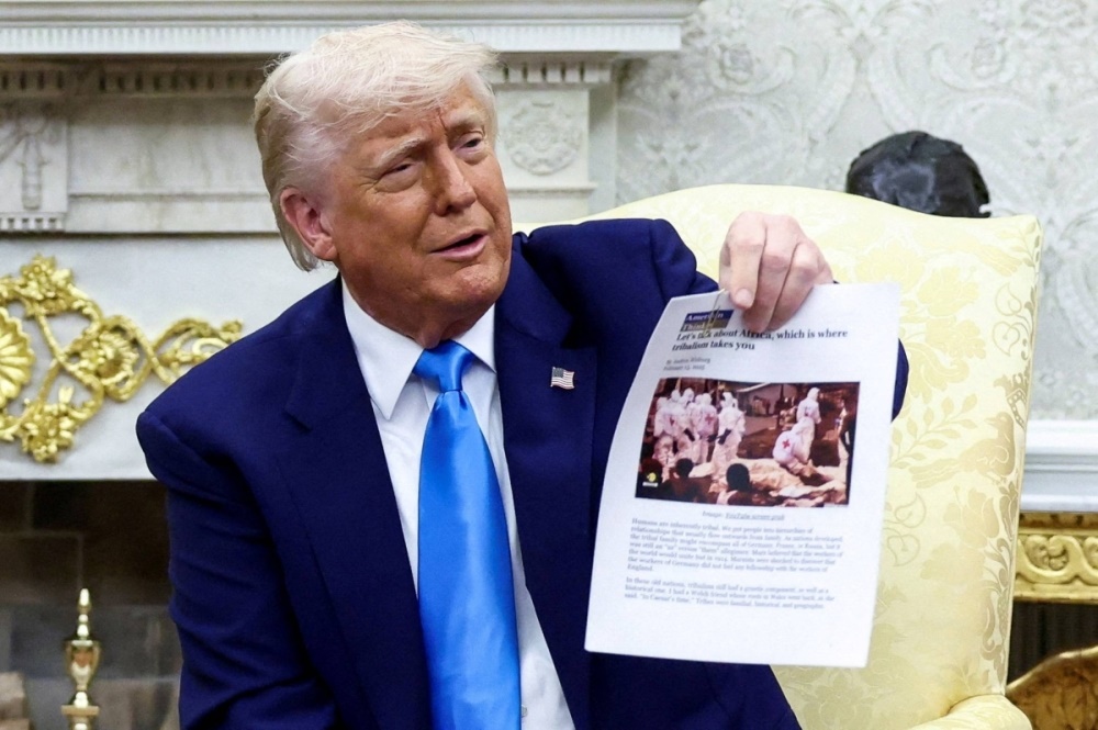 U.S. President Donald Trump shows a copy of an article he said is about white South Africans who had been killed, in the Oval Office of the White House in Washington on Wednesday. | REUTERS
