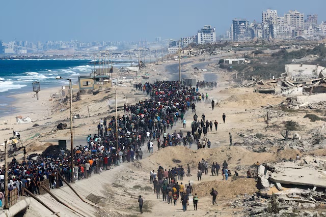 Palestinians, who were displaced to the southern part of Gaza at Israel's order during the war, walk along a road as they attempt to return to the north after a ceasefire, in the central Gaza Strip, October 10. REUTERS/Mahmoud Issa