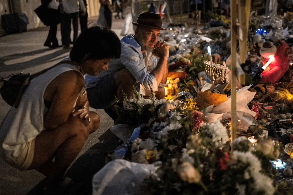 People take a moment of silence after lighting a candle for the victims of a mass shooting during a Jewish Hanukkah celebration at Bondi Beach on December 14, in Sydney, Australia, December 20, 2025. REUTERS/Eloisa Lopez