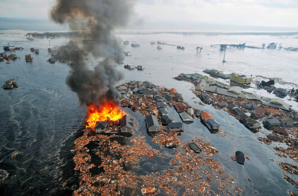Houses are swept by water following a tsunami and earthquake in Natori City in northeastern Japan, March 11. REUTERS/Kyodo