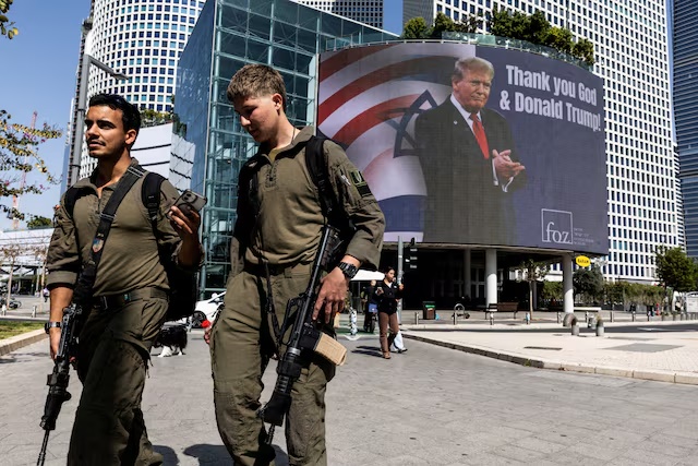 Israeli soldiers walk by a billboard commissioned by an evangelical group, which displays a picture of U.S. President Donald Trump with the words "Thank you God & Donald Trump", amid the U.S.-Israel conflict with Iran, in Tel Aviv, Israel, March 12, 2026. REUTERS/Nir Elias/File Photo