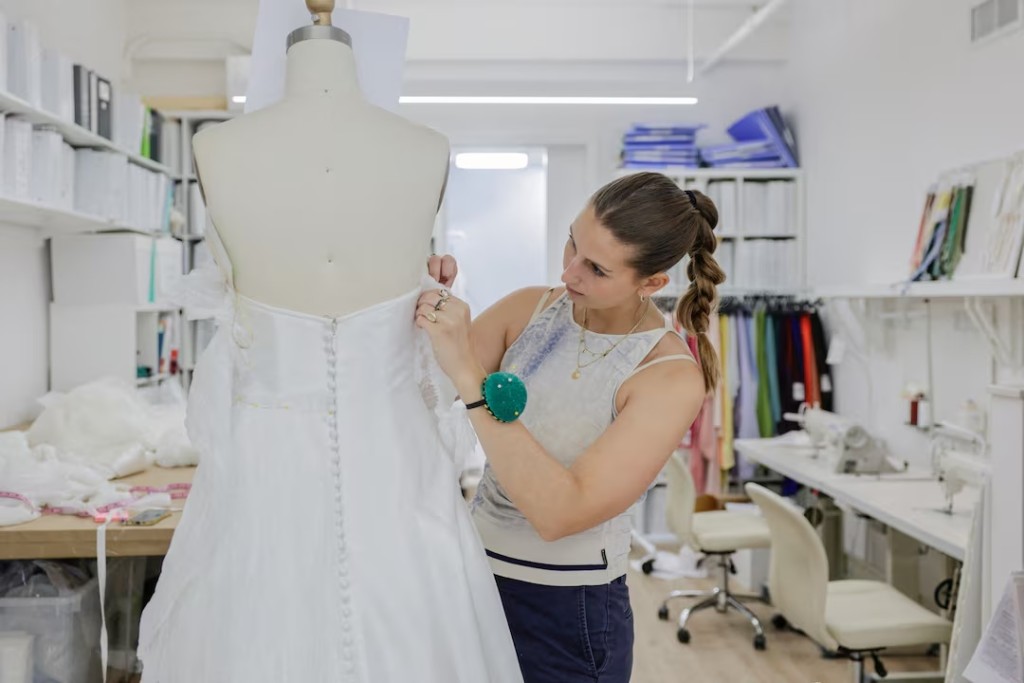  Designer Kat Eberley works on a dress at the Jenny Yoo bridal boutique in New York City, U.S., August 6, 2026. REUTERS/Jeenah Moon