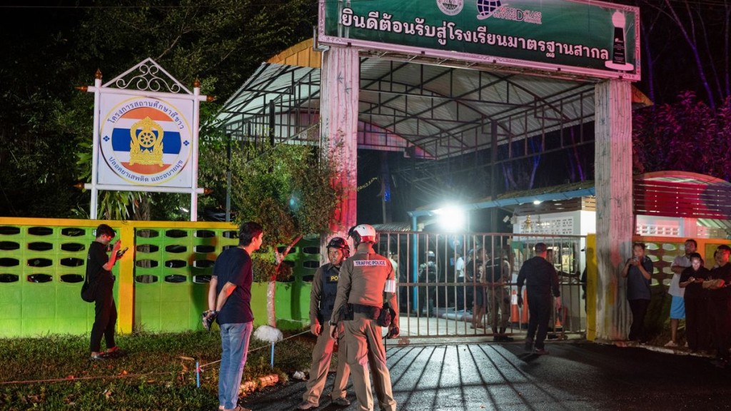 Police officers and people stand near the gate of Patongprathankiriwat School. Reuters