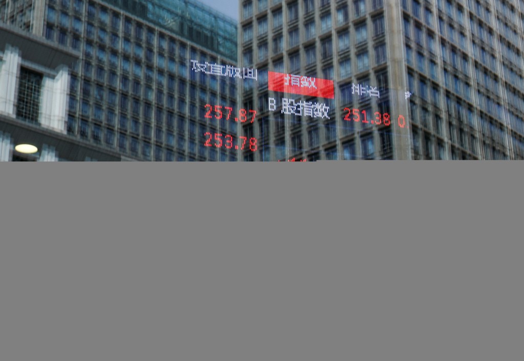 A person and buildings are reflected on the glass of a brokerage house where a display board is hung inside showing the stock index information, in Beijing, China April 9, 2025. REUTERS