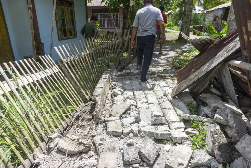 People past damage in a residential area caused by a magnitude 7.8 earthquake off the southern Philippines, at Peta Timur village in Sangihe Islands Regency, Indonesia's North Sulawesi province on June 8, 2026. (AFP)