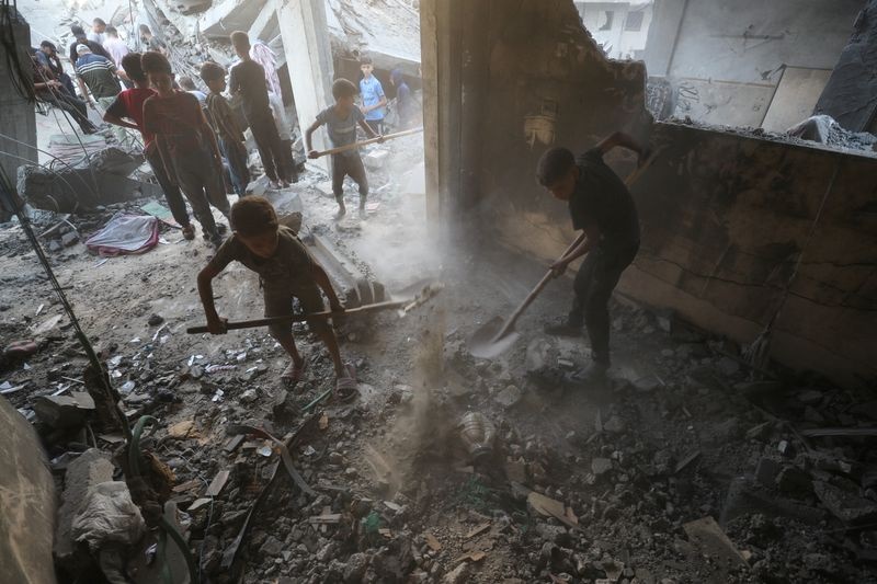 © Reuters. Children shovel the dirt, as Palestinians look for casualties amid the damage, at the site of an overnight Israeli strike on a house, at Shati (Beach) refugee camp in Gaza City, July 9, 2025. REUTERS/Mahmoud Issa/File Photo