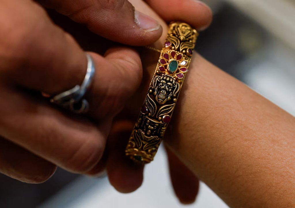 A woman puts on a bangle at a jewellery store in Mumbai, India, March 20, 2025. REUTERS