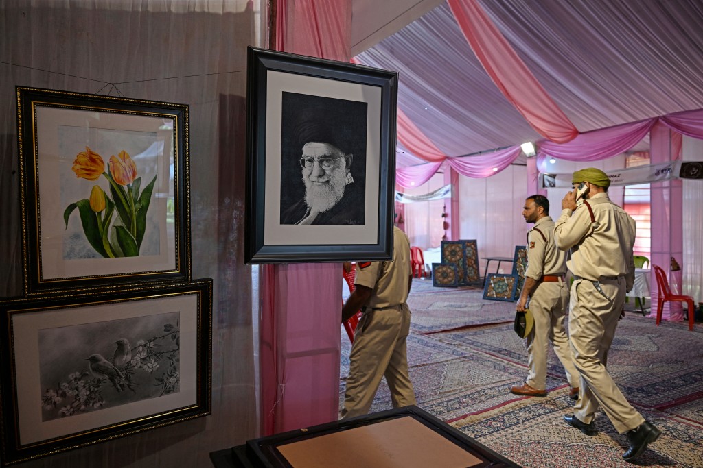 Police walk past a portrait of Iran's late supreme leader Ayatollah Ali Khamenei, displayed at a stall during an exhibition in Srinagar on September 9, 2026. (Photo by Tauseef MUSTAFA / AFP) 