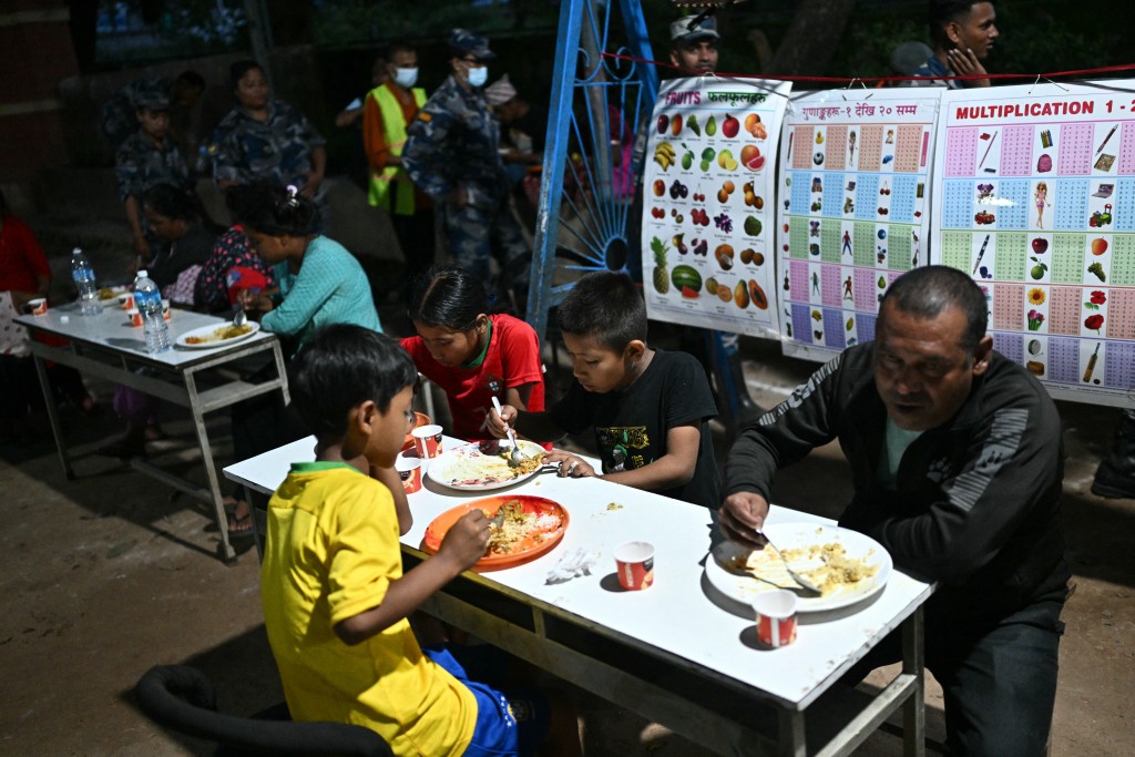 Photo by PEDRO PARDO / AFP  Flash flood survivors eat food inside a relief shelter at Devighat in Nepal's Nuwakot district on September 8, 2026.