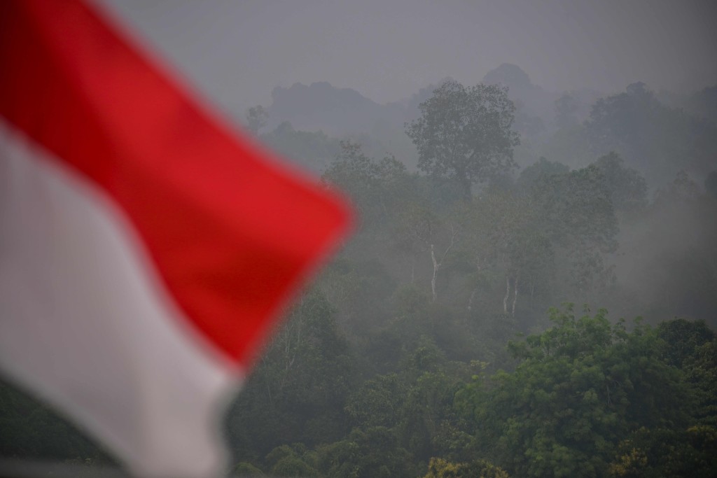 An Indonesia flag waves in front of trees blanketed by haze from the forest and land fires in Putussibau, West Kalimantan on September 5, 2026. (Photo by BAY ISMOYO / AFP)