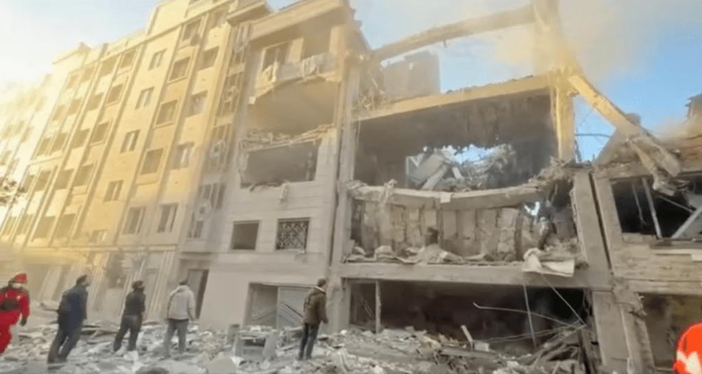 People stand near damaged buildings, amid the U.S.-Israeli conflict with Iran, in Tehran, Iran, in this still image obtained from a handout video released on April 1, 2026. Iranian Red Crescent Society/Handout via REUTERS