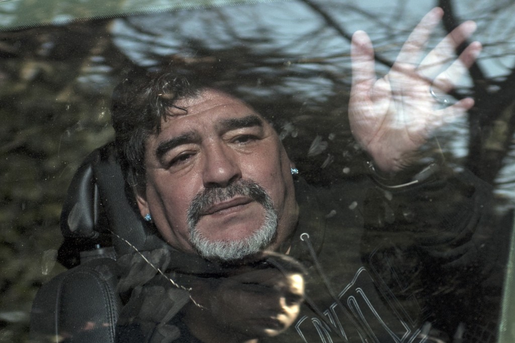 Photo by EITAN ABRAMOVICH / AFP  Argentina's former football star Diego Armando Maradona waves to supporters as he leaves the funeral of his father "Don Diego", in Bella Vista, outskirts of Buenos Aires, on June 26, 2015."