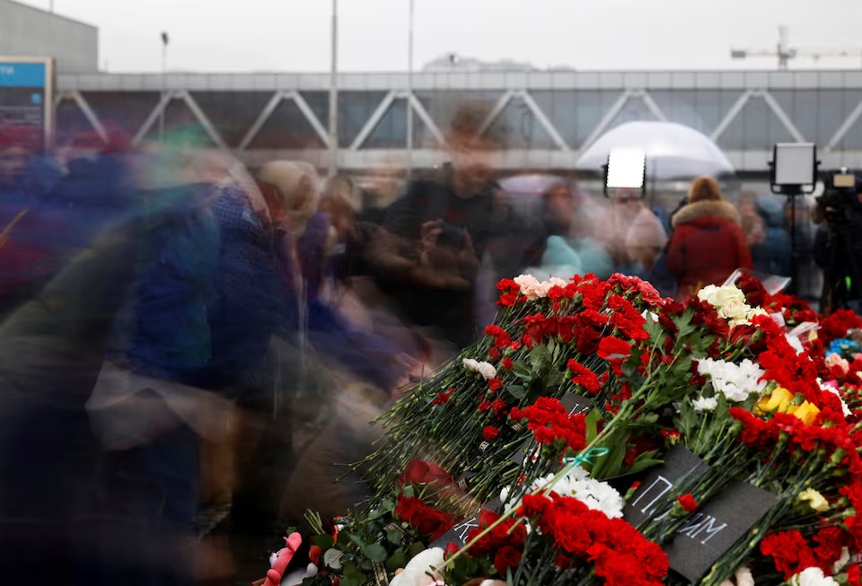 People lay flowers at a makeshift memorial to the victims of a shooting attack, set up outside the Crocus City Hall concert venue in the Moscow Region, Russia, March 24, 2024. (REUTERS/Maxim Shemetov)