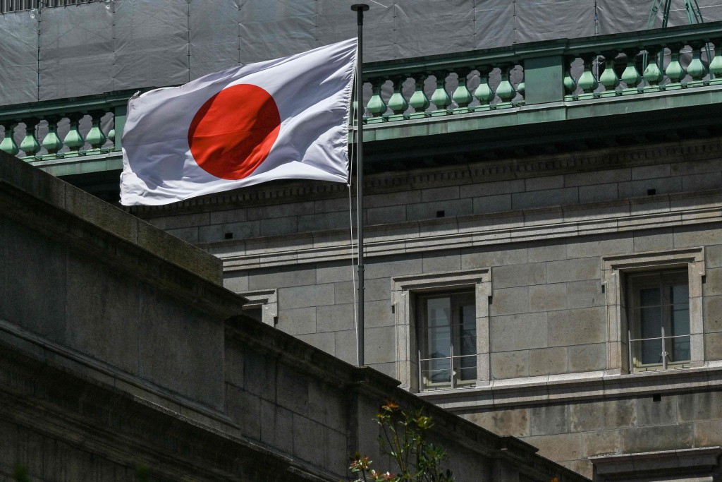 The Japanese flag flutters in the wind from the top of the Bank of Japan (BoJ) headquarters complex in central Tokyo on June 16, 2025. AFP
