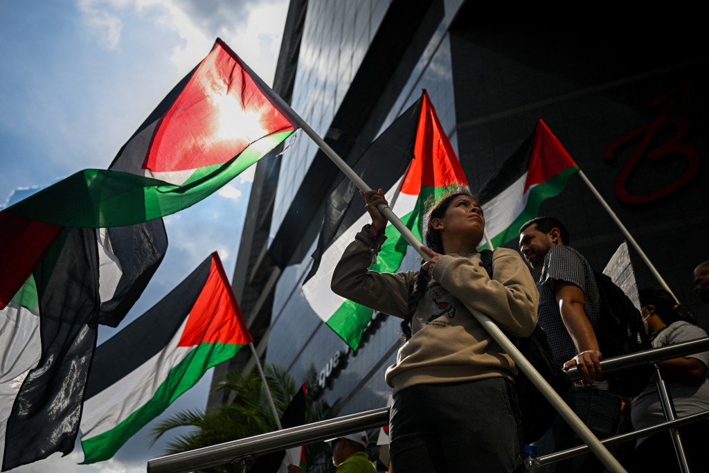 A woman holds a Palestinian flag during a protest in solidarity with Palestinians and to condemn the interception of the Global Sumud Flotilla by the Israeli army, in Caracas on October 2, 2025. (Photo by Federico PARRA / AFP)