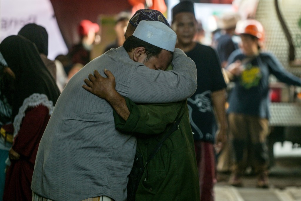 Relatives of missing students mourn as search and rescue operations continue at the Al Khoziny Islamic boarding school in Sidoarjo, East Java province on October 1, 2025, after a multi-storey building at the school collapsed. A second survivor was pulled on October 1, from the rubble of a school that collapsed in Indonesia two days earlier, authorities said. (Photo by Juni KRISWANTO / AFP)