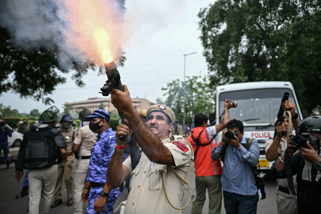 Photo by SAJJAD HUSSAIN / AFP  A police personnel fires tear gas shells to disperse activists and supporters of the Cockroach Janta Party (CJP) during a protest demanding the resignation of India's Education Minister Dharmendra Pradhan over alleged NEET examination irregularities in New Delhi on July 20, 2026.