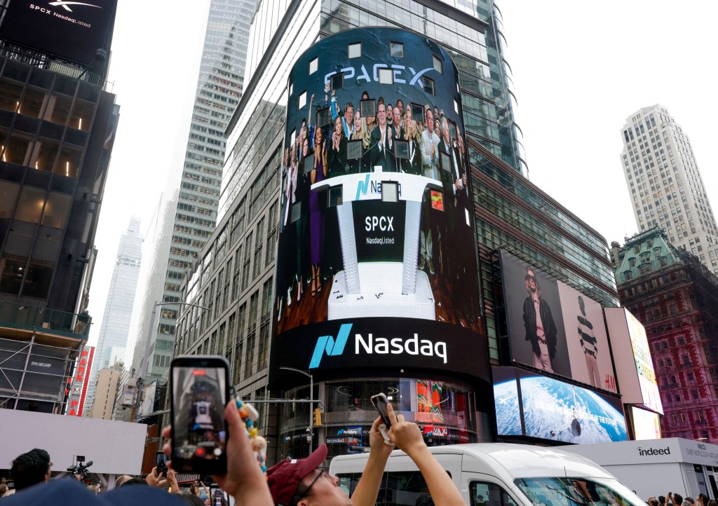 People gather to watch a live feed with SpaceX CEO Elon Musk on the day of SpaceX's initial public offering (IPO) at the Nasdaq MarketSite, in New York City, U.S., June 12, 2026. REUTERS/Jeenah Moon